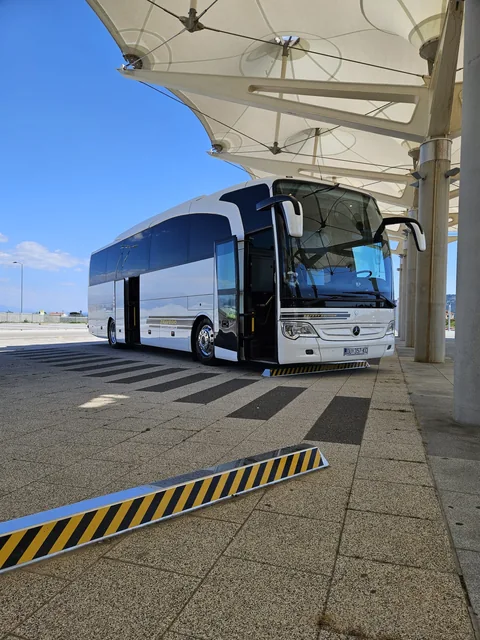 Front view of a white coach at a covered pickup area