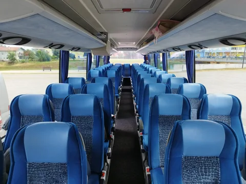 Rows of blue seats and overhead shelves inside a coach